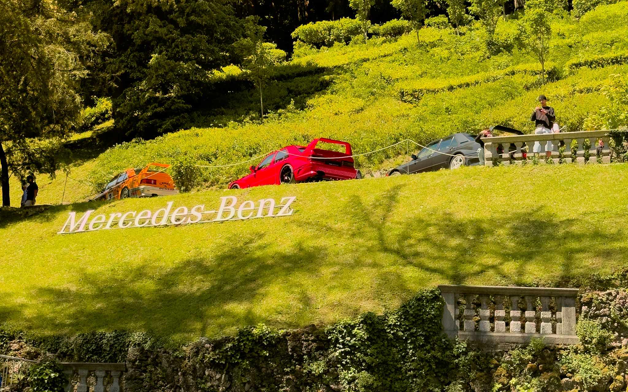 Three 190E EVOs on the hillside beneath the Mercedes-Benz sign